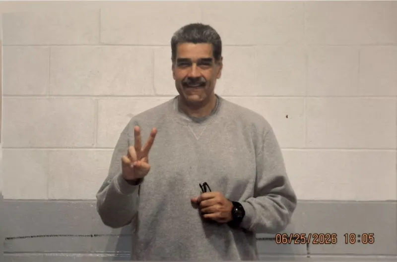 Con un fondo de color gris y blanco, Nicolás Maduro aparece con una sudadera gris, haciendo la señal de paz con una mano, sosteniendo sus lentes y un reloj en su muñeca izquierda.