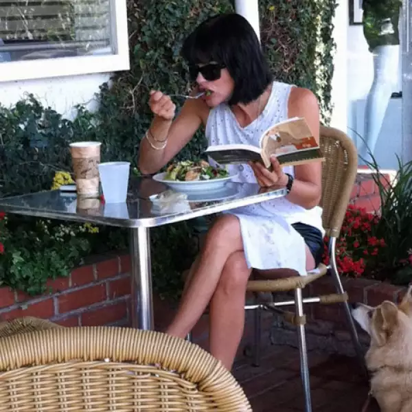 A la bella actriz Selma Blair le gusta comer mientras lee un libro y está acompañada de su linda mascota.