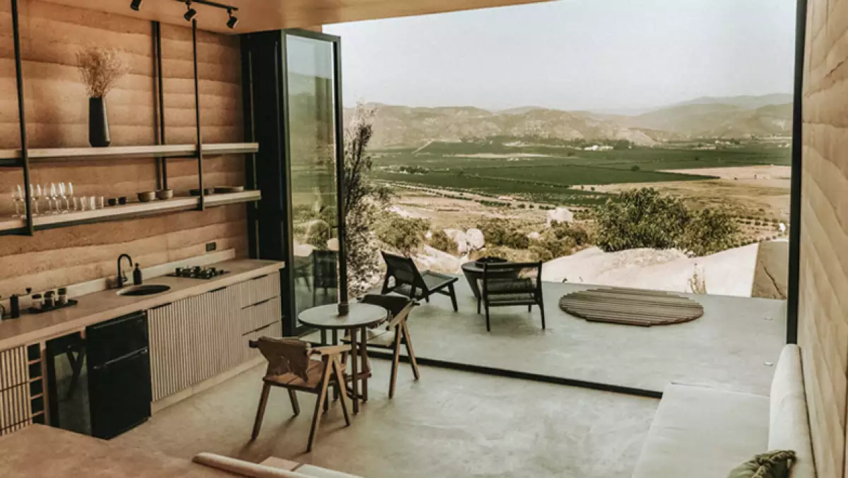 Foto de una de las habitaciones de MIRA Earth Studios con el balcón abierto y la vida del Valle de Guadalupe desde la montaña.