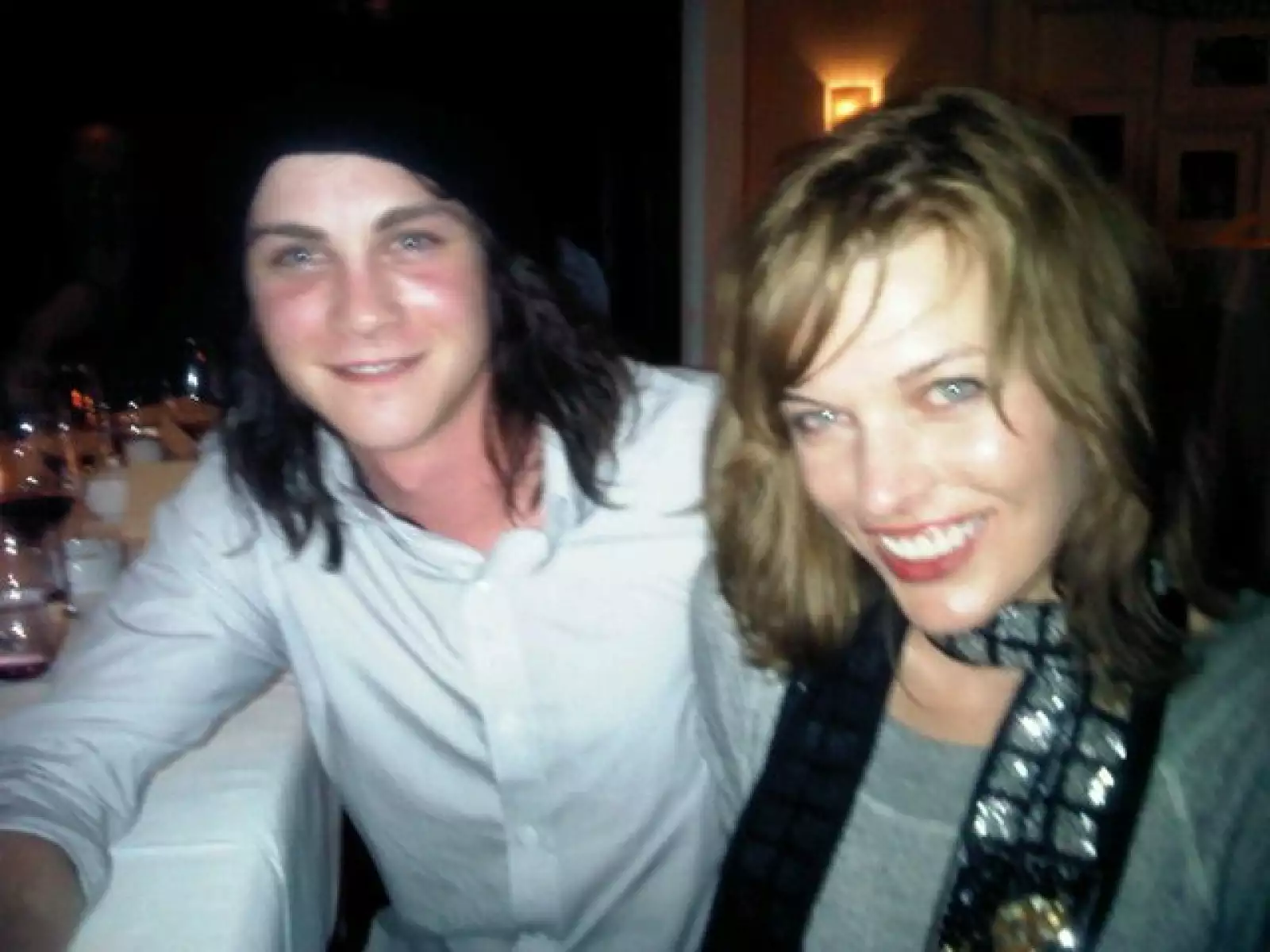 La actriz Milla Jovovich sonriente y acompañada.