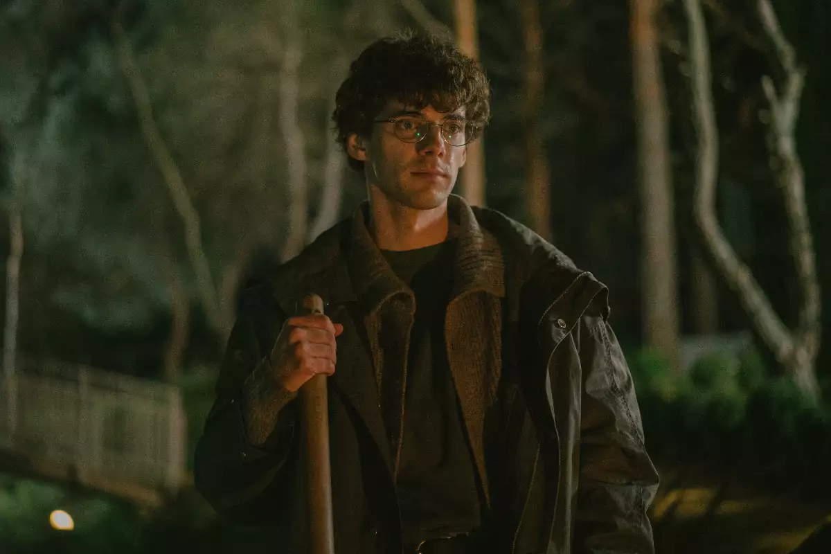 Foto del actor Álvaro Rico en su papel de Elmer en 'El Jardinero', en un bosque a oscuras y con una pala en la mano.