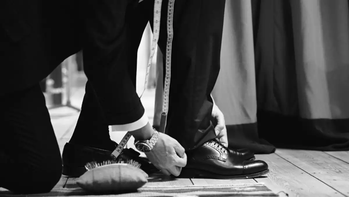 Foto de un sastre midiendo el largo de un pantalón.