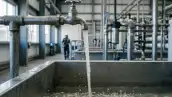 Grifo de agua abierto y en el fond una instalación de una fábrica.