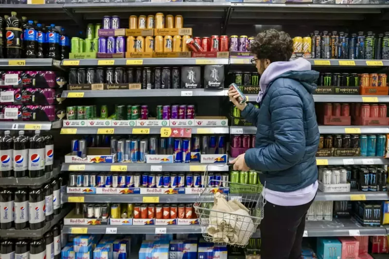 Latas de bebidas energetizantes en una tienda con un comprador que la examina. La venta de bebidas energéticas ya no “activa” al fisco: su recaudación cayó 75% desde 2022 y ahora podrían prohibirse a menores de edad.

