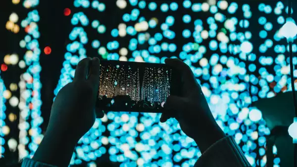 Hands holding mobile phone above head, taking photos.