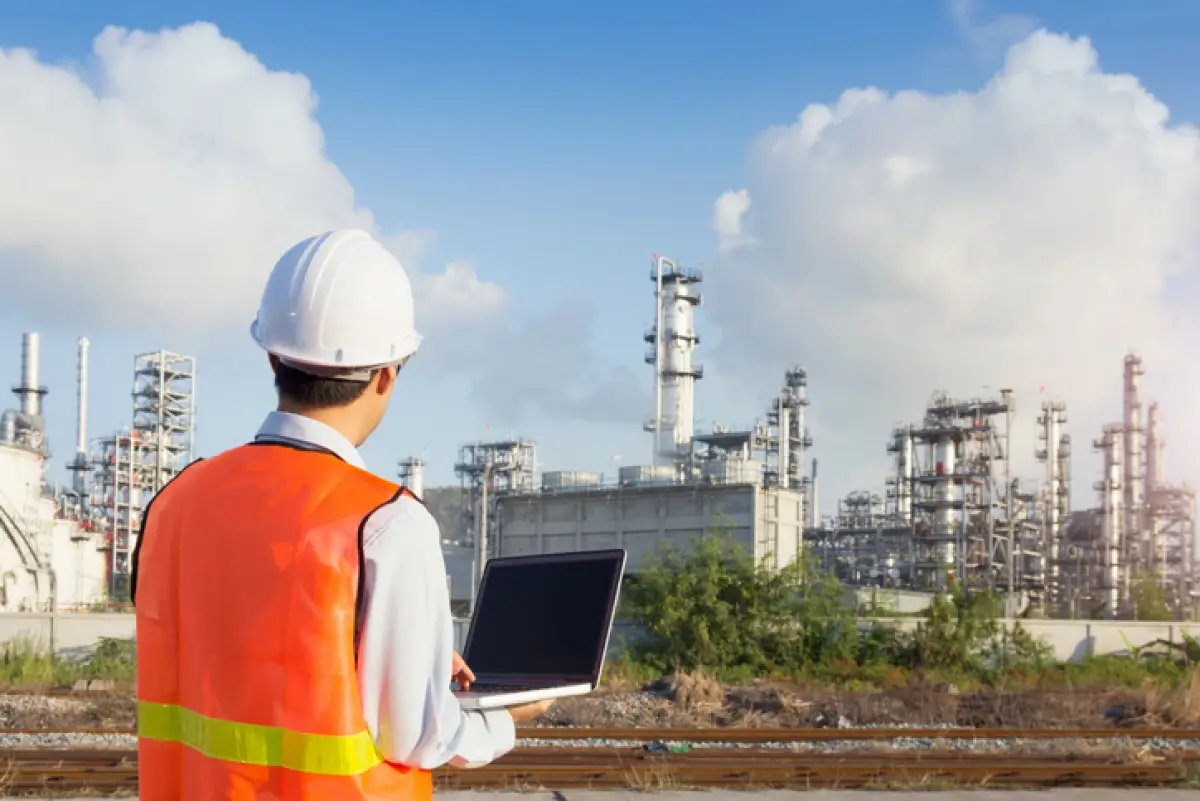 Maintenance engineer working with laptop in oil refinery