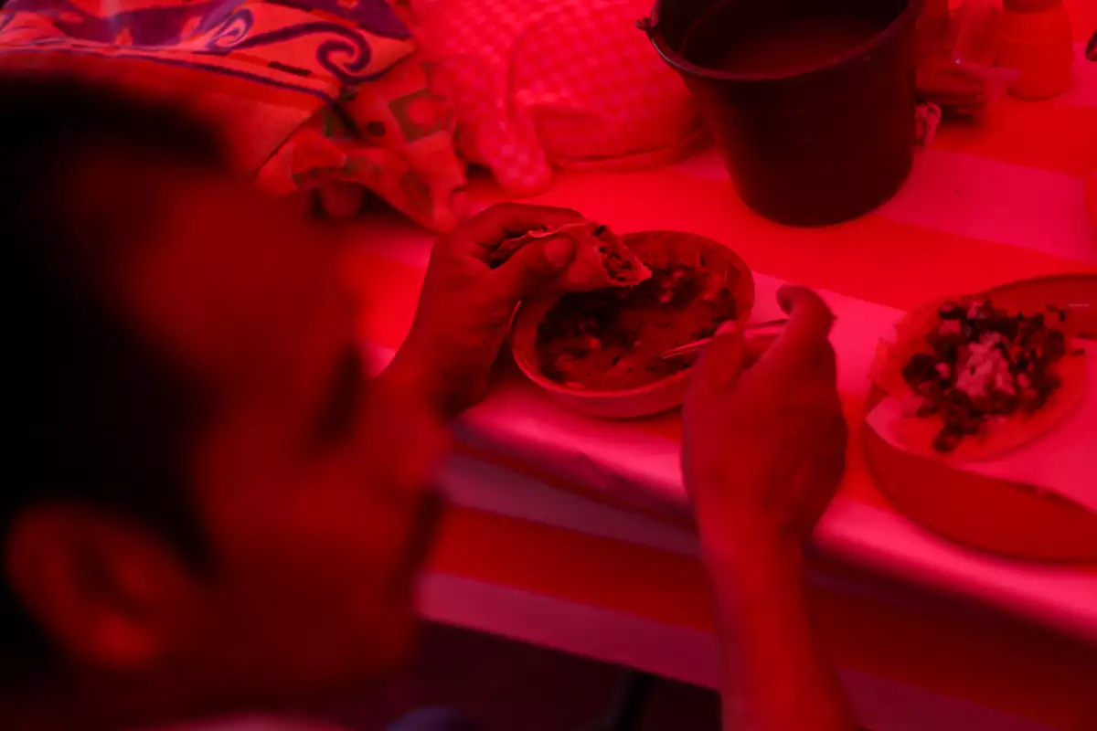 (Un hombre come tacos en un puesto callejero)
