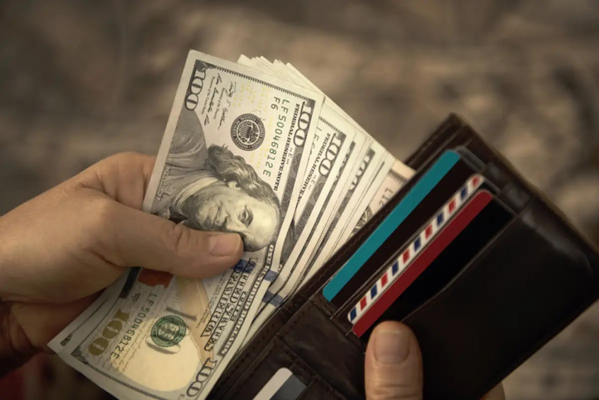 High angle view of unrecognizable mature man placing USA Dollar bills into wallet