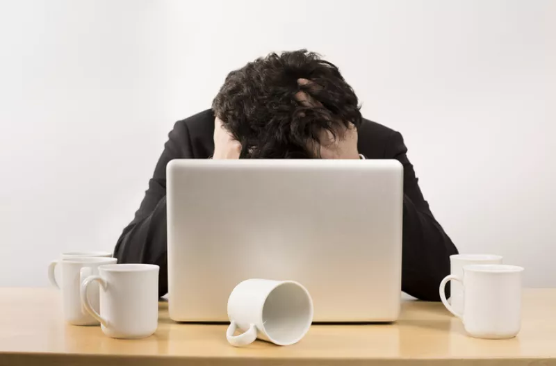 Stressed businessman at desk with several empty coffee cups