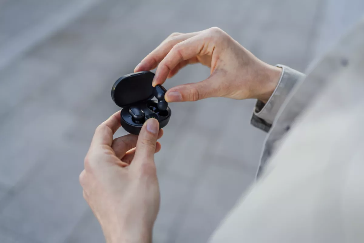 Man taking out a wireless earbud from charging box