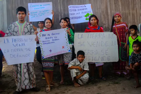 Personas indígenas con pancartas donde se lee el mensaje "La tierra no se vende, la tierra se defiende".