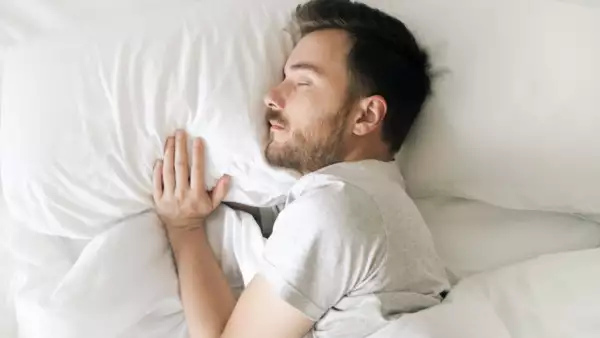 Hombre durmiendo sobre dos almohadas