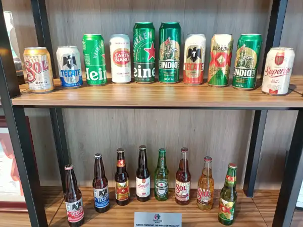 Latas de cervezas en colores verde, blancas, azules y amarillas, con nombres como Indio, dos equis, Heineken.jpeg