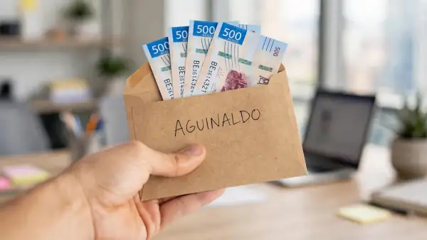 Un sobre con dinero y aguinaldo escrito, en el fondo una oficina.