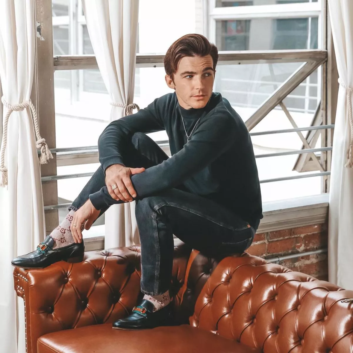 Drake Bell sentado en un sillón de piel