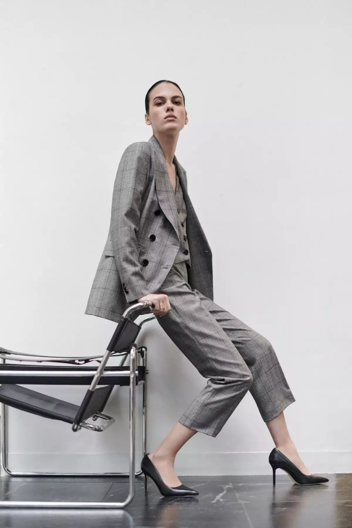 Mujer vestida con pantalón y saco grises posa en una oficina, con ropa de la marca DHierro de El Palacio de Hierro