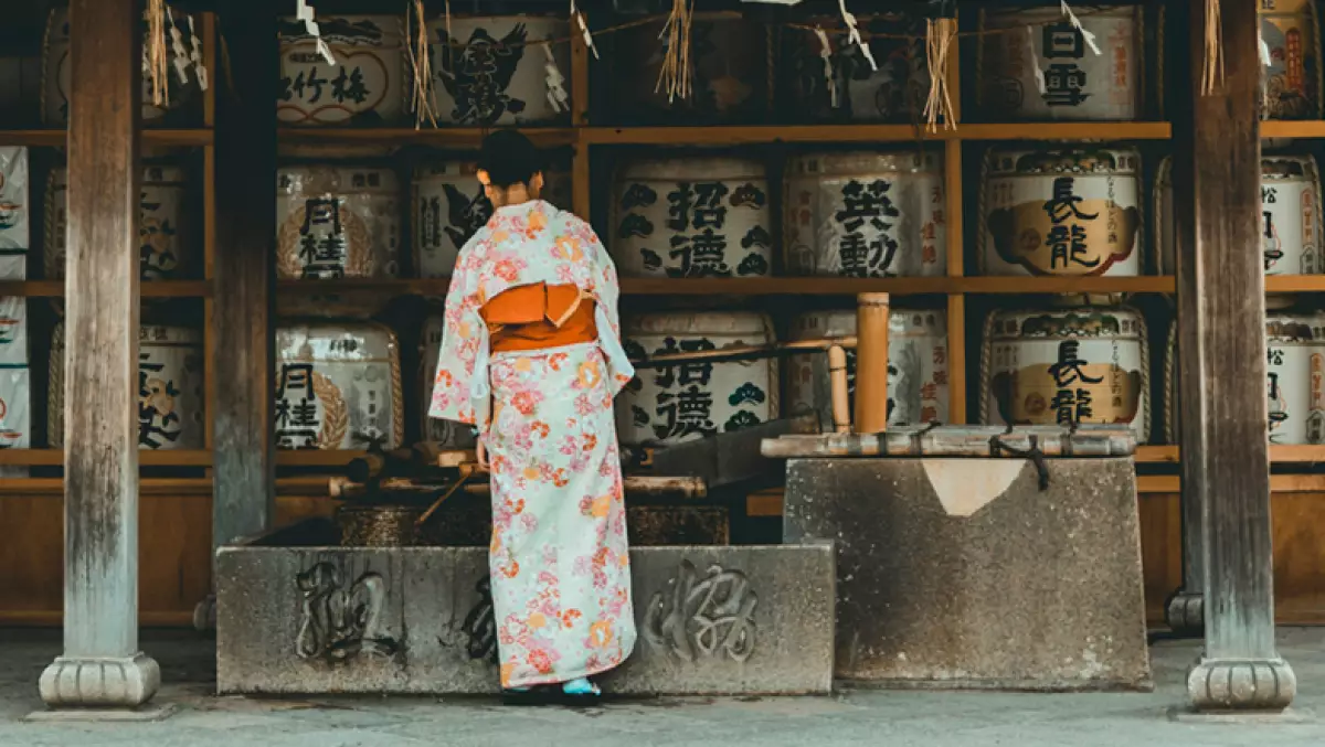 Foto de una mujer con traje típico japonés frente a un templo
