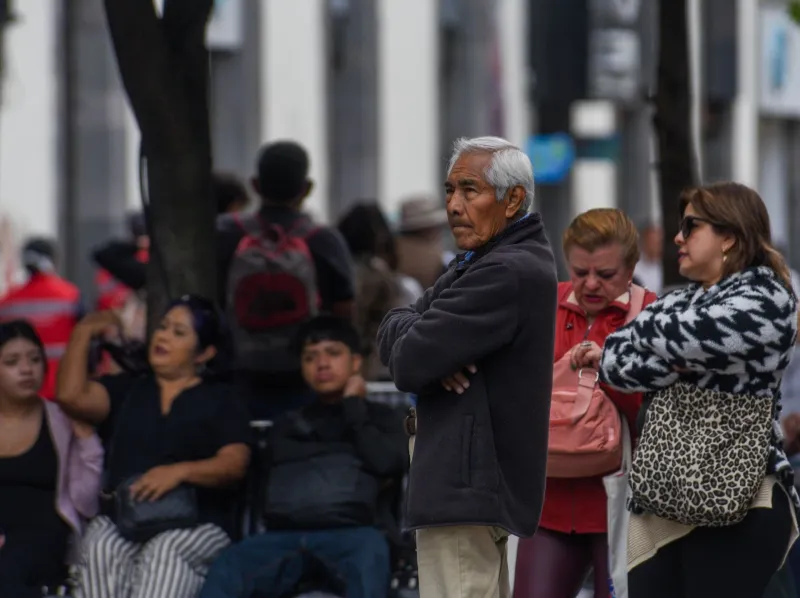 Adultos mayores en la calle entre jóvenes.