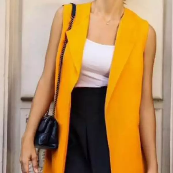 Adriana en París  con un look conformado por un chaleco naranja largo, una falda negra y un top