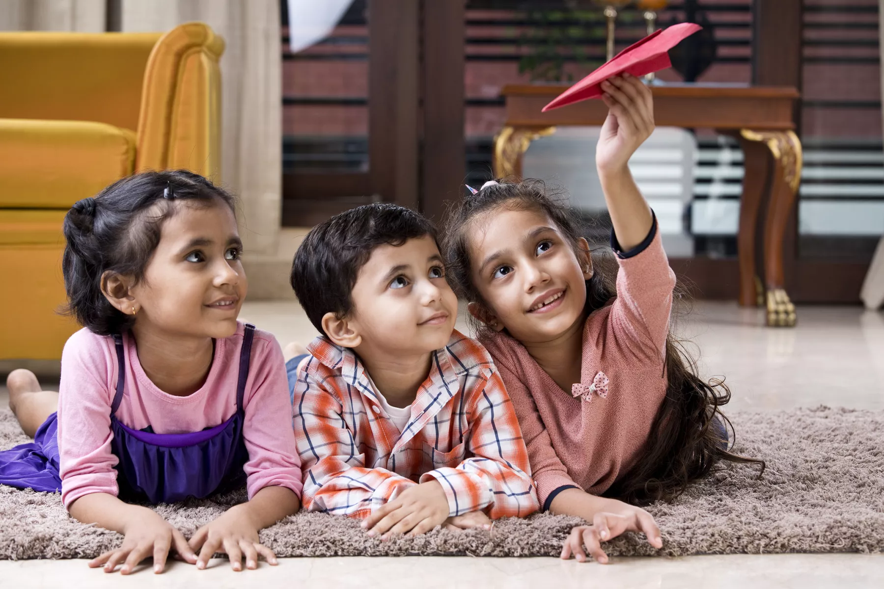 Children playing with paper airplane at home