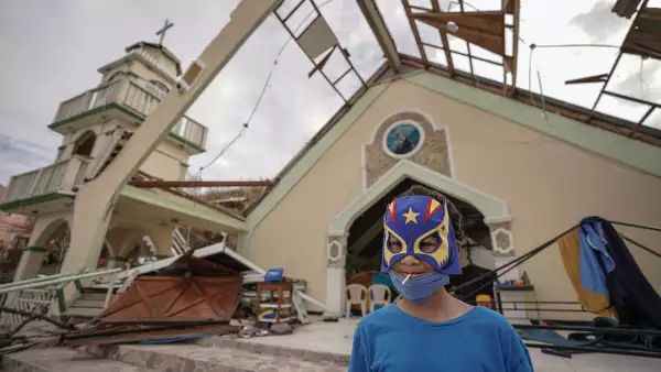 Un niño con una máscara disfrazada sonríe frente a una iglesia que se utiliza como refugio improvisado el 21 de noviembre de 2020 en la isla de Providencia, Colombia.