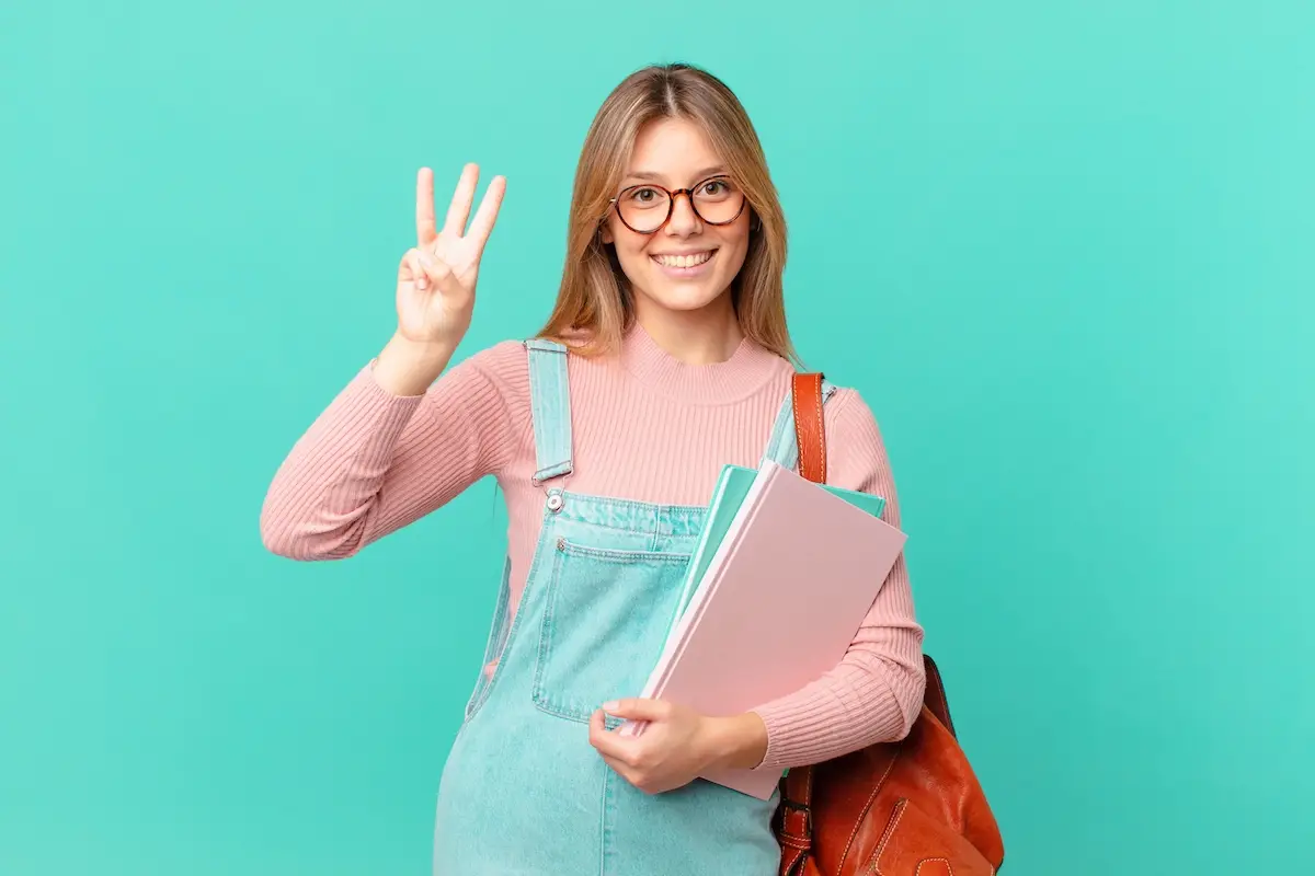 Young,Student,Woman,Smiling,And,Looking,Friendly,,Showing,Number,Three