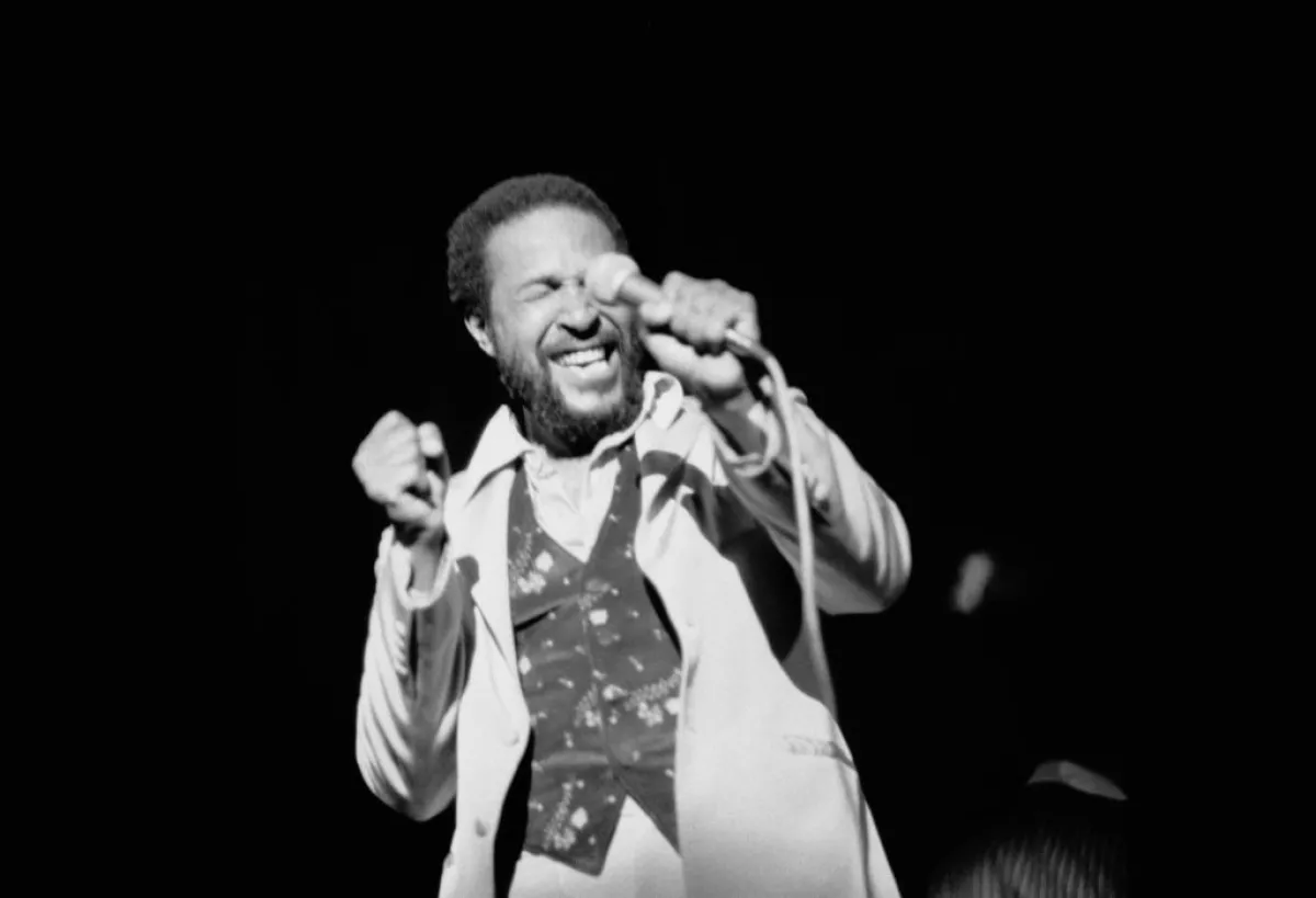 Foto en blanco y negro de Marvin Gaye durante un concierto con un micrófono en mano.