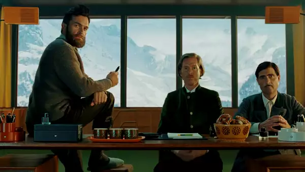 tres hombres ante un escritorio con plumas estilográficas y papeles, al fondo se observa el Mont Blanc.