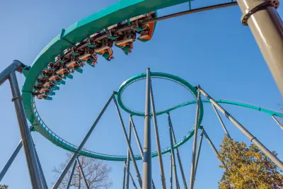 Montaña rusa Goliath de Six Flags con pasajeros recorriendo una curva elevada bajo un cielo despejado.