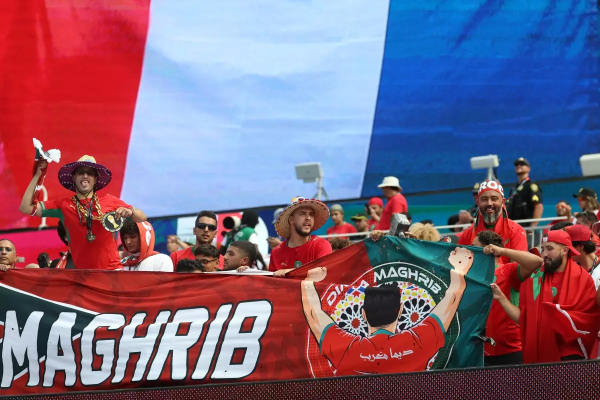 Los fanáticos marroquíes animan a su equipo con una bandera francesa en el fondo antes del partido de cuartos de final del torneo de la Copa Mundial de fútbol de 2026 entre Francia y Marruecos en el Estadio de Boston en Foxborough el 9 de julio de 2026.