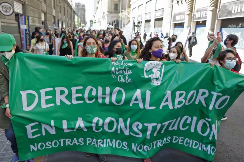 Mujeres sostienen una pancarta que dice "Derecho al aborto en la Constitución" durante una demostración afuera del antiguo Congreso Naciones, en Santiago de Chile. 