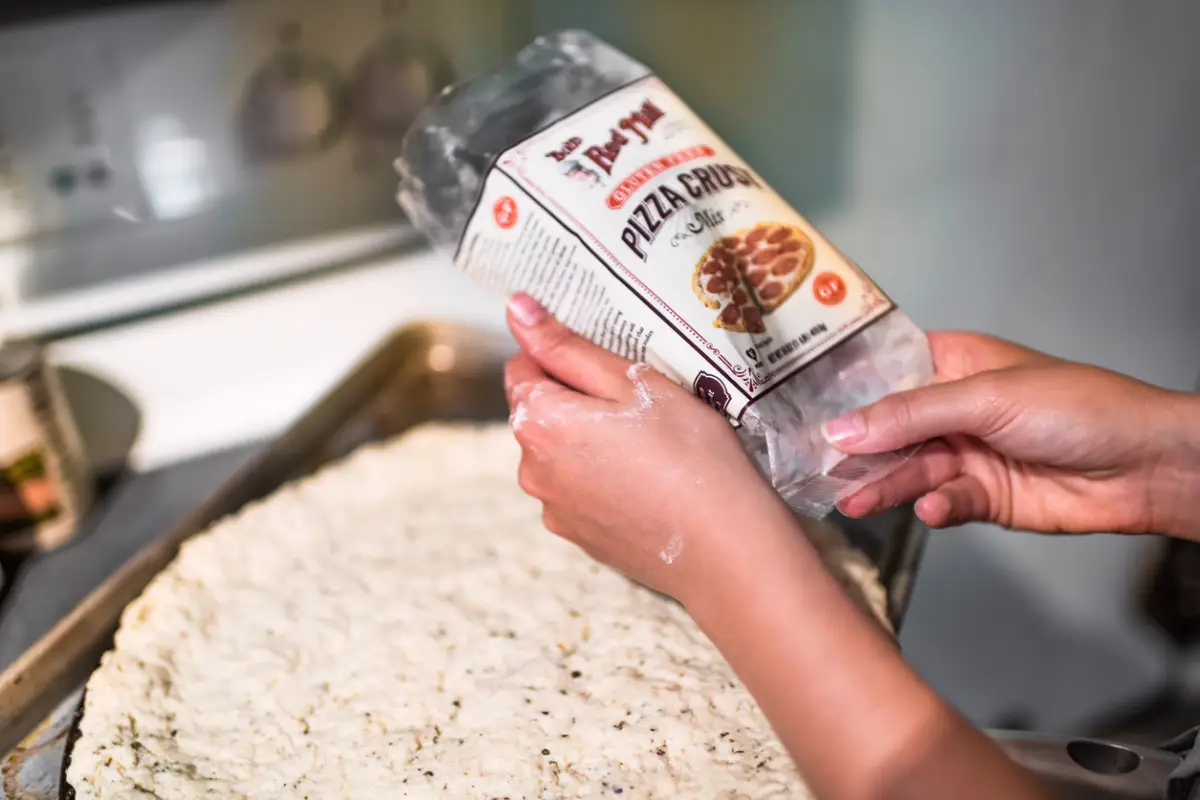 Baking pan with uncooked pizza dough before baking made with gluten free flour Bob's Red Mill brand of packaged mix