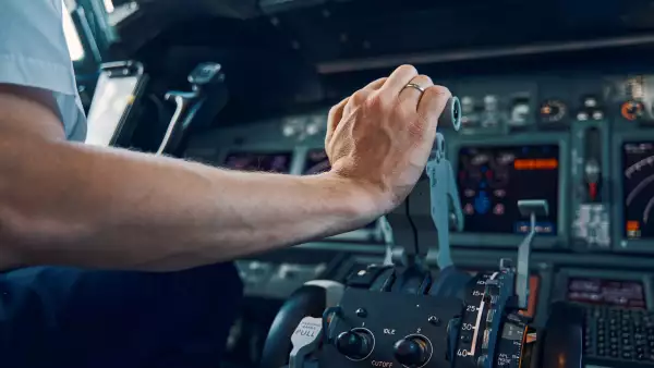 Se muestra la mano de un piloto desde la cabina de un avión. 
