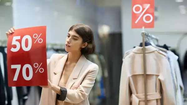 (Trabajadora de una tienda coloca anuncios de ofertas en un escaparate)