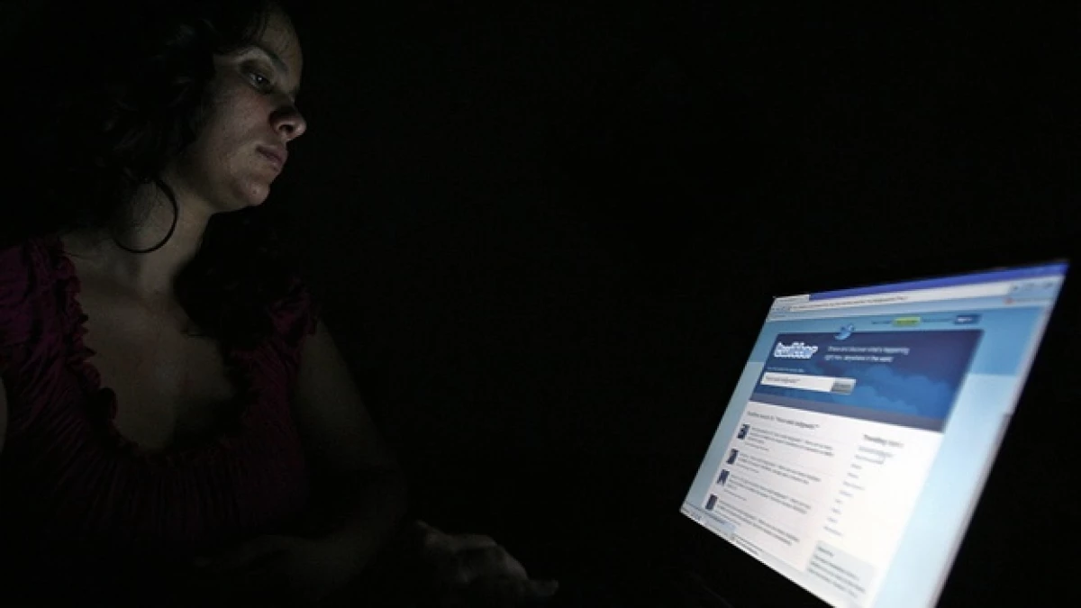 una chava frente a una pantalla donde se ve la pagina de twitter