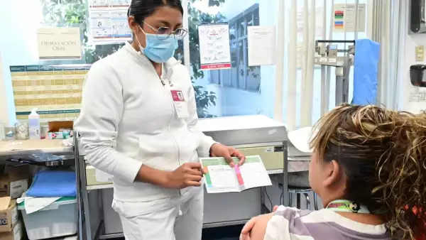 Una enfermera muestra la cartilla de vacunación a una paciente en México