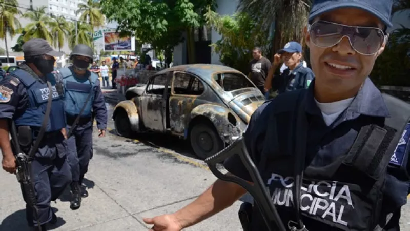 policías rodean un auto incendiado