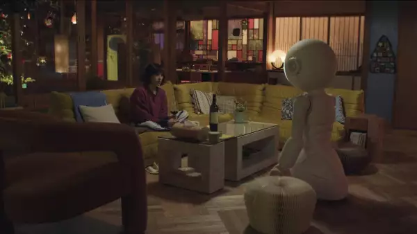 Foto de una escena de Sunny, donde se ve a un robot de cabeza redonda de frente a Suzy (interpretada por Rashida Jones) en lo que parece un puente rodeado de agua.