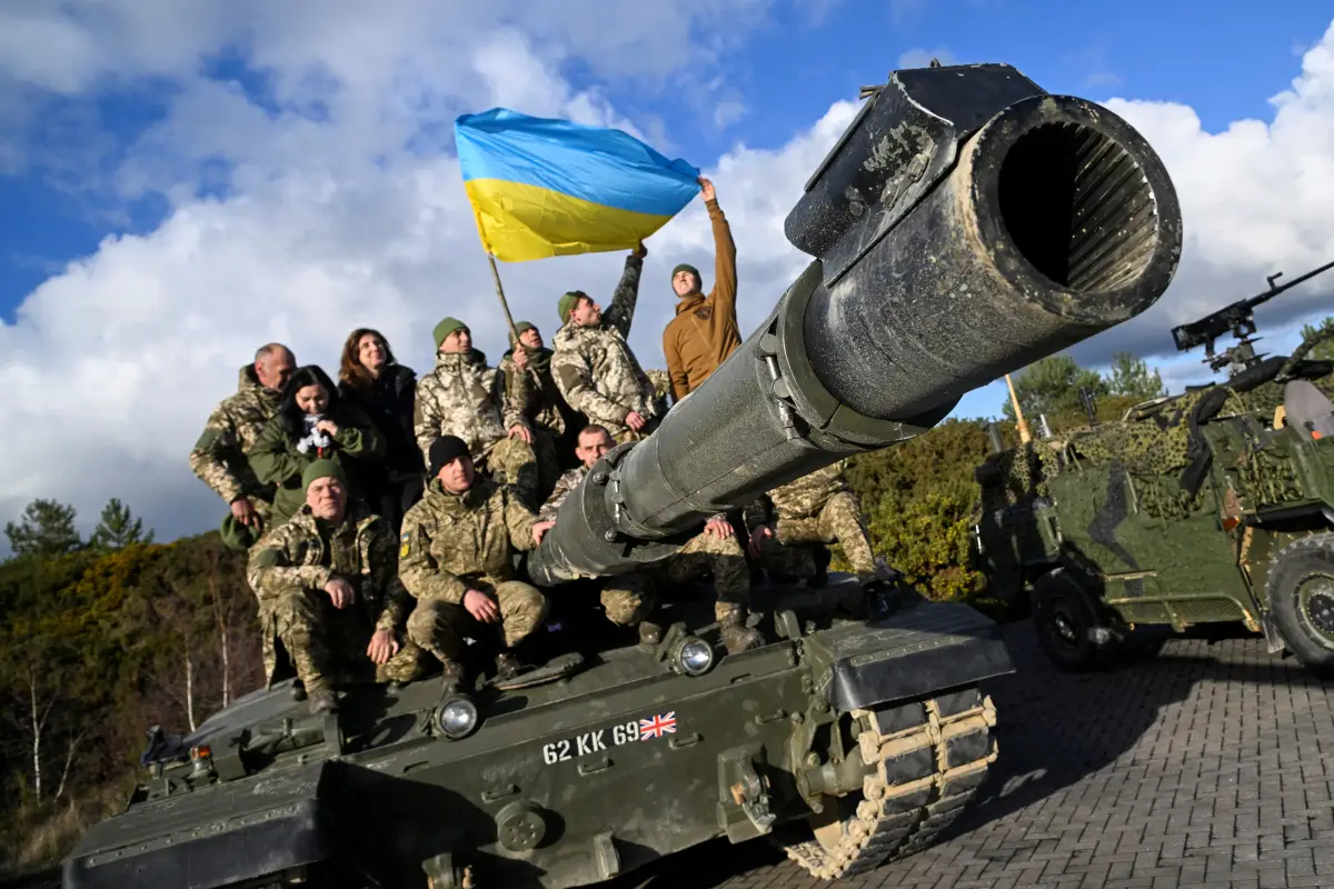 El personal ucraniano posa con una bandera encima de un tanque Challenger 2 durante un entrenamiento en el campamento de Bovington, cerca de Wool en el suroeste de Gran Bretaña, el 22 de febrero de 2023.