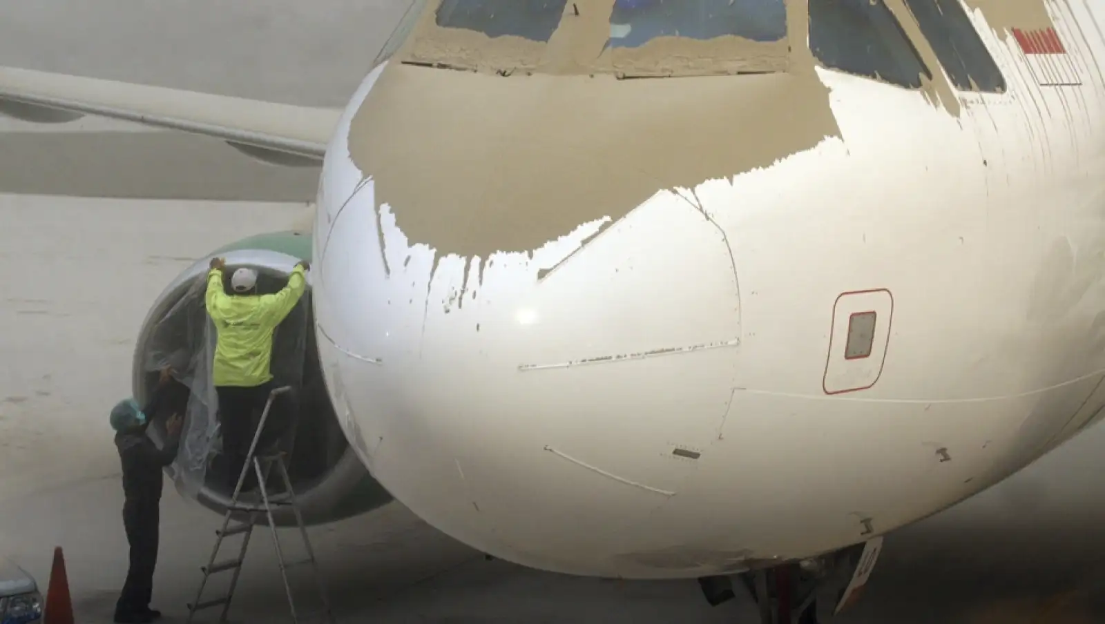 trabajadores limpian un avion de cenizas