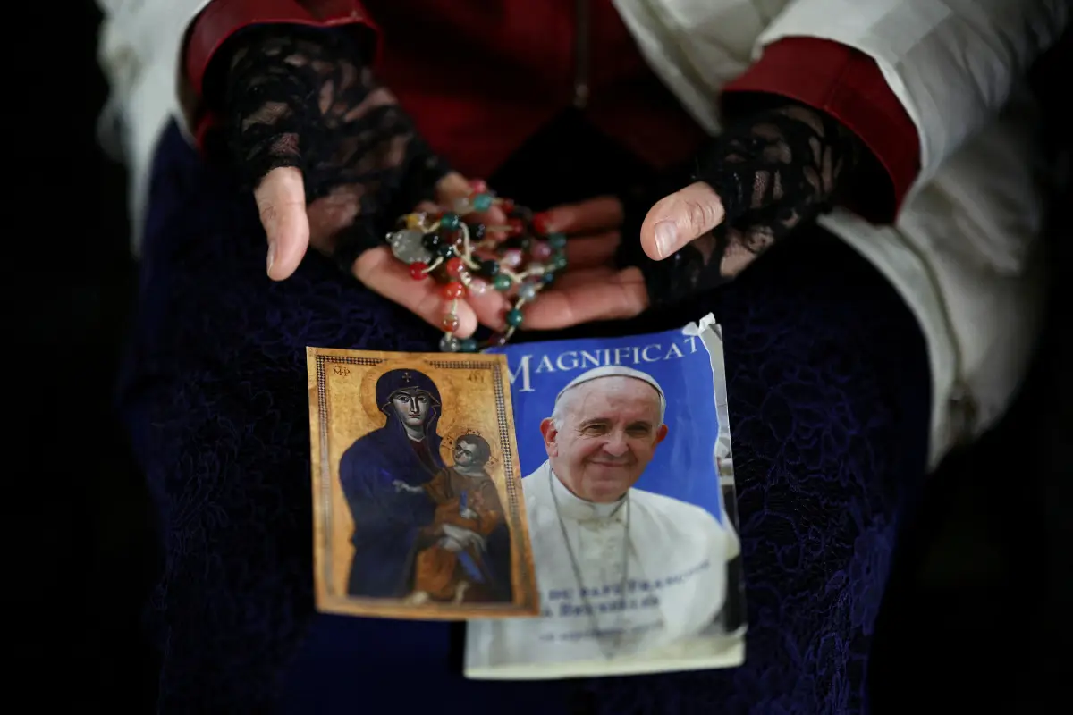 Una persona sostiene una imagen del Papa Francisco antes de un servicio de oración en St. Plaza de San Pedro mientras continúa el tratamiento en el Hospital Gemelli del Vaticano, 24 de febrero de 2025.