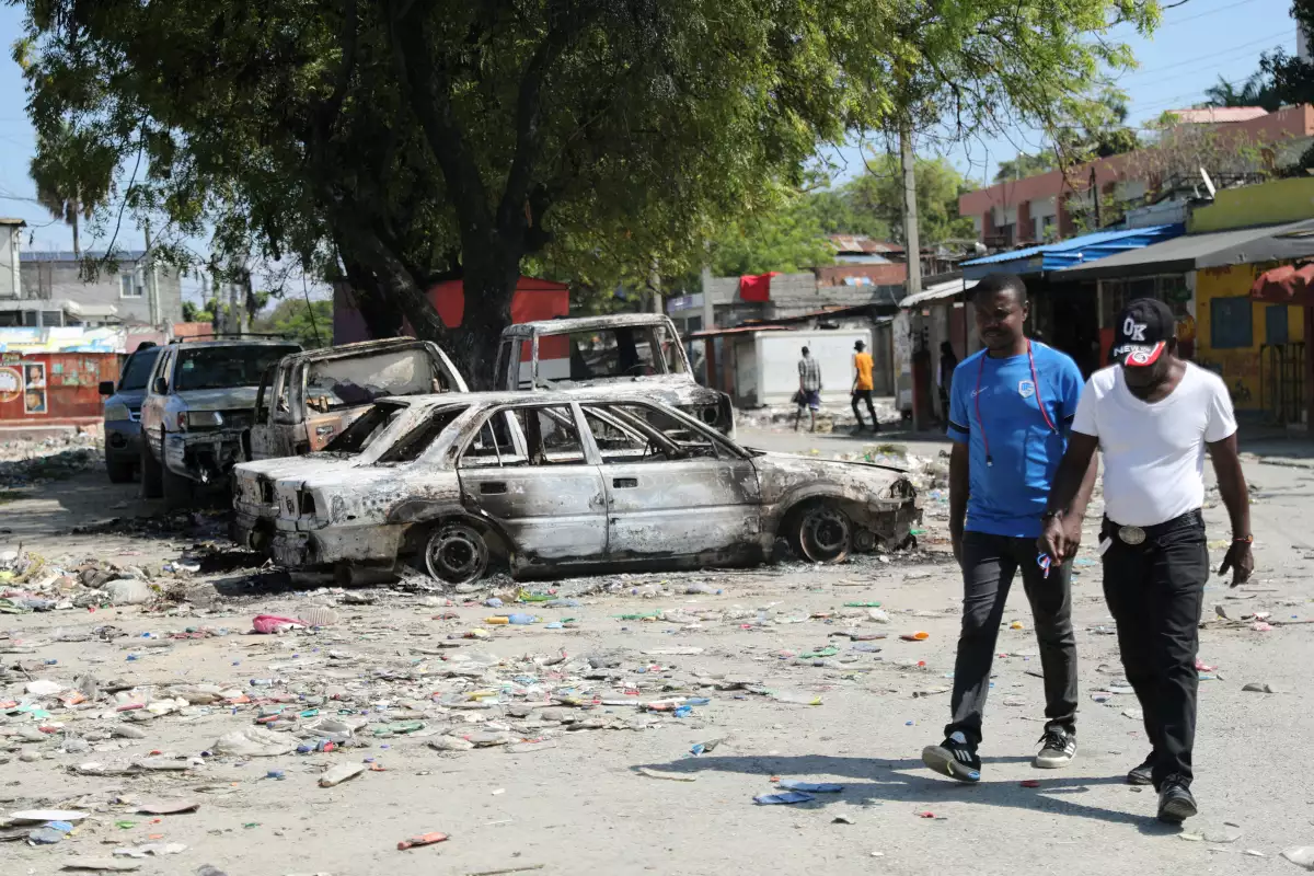 ¿Qué está pasando en Haiti en 2024? En esta imagen, la gente camina cerca de los coches consumidos por un incendio, ya que Haití permanece en estado de emergencia debido a la violencia, en Puerto Príncipe, el 9 de marzo.