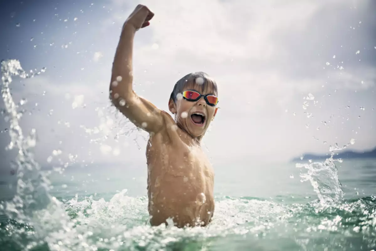 Little boy playing and splashing in sea waves