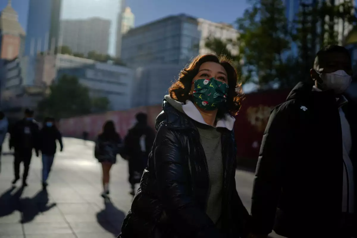 Gente usando mascarillas protectoras caminan en un distrito comercial en Shanghai, mientras China regresa a trabajar a pesar de que el brote de covid-19 continúa. 