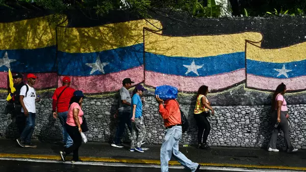 La gente se para frente a un mural con una bandera venezolana en Caracas el 7 de enero de 2026. La administración del presidente de los Estados Unidos, Donald Trump, dijo el 7 de enero que tiene la intención de dictar las decisiones de los líderes interinos de Venezuela y controlar las ventas de petróleo del país "indefinidamente" después de derrocar a Nicolás Maduro.