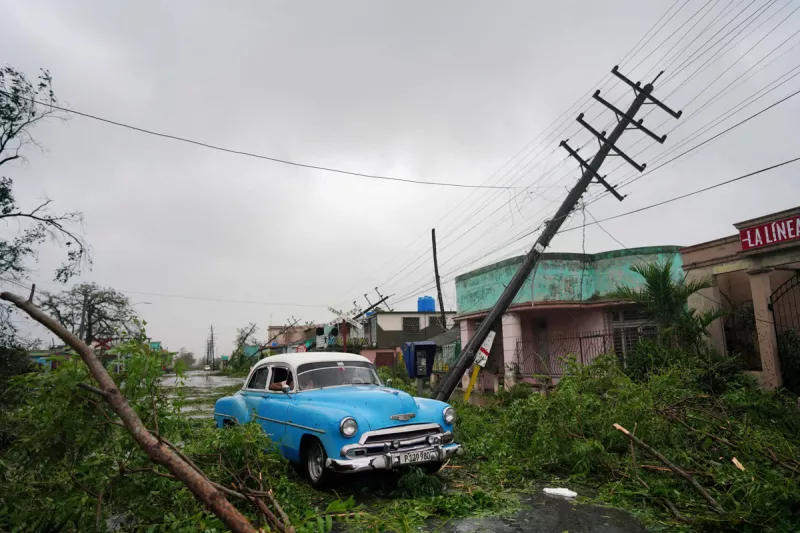 Un coche antiguo pasa por los escombros causados por el huracán Ian cuando pasó en Pinar del Río, Cuba, el 27 de septiembre de 2022.
