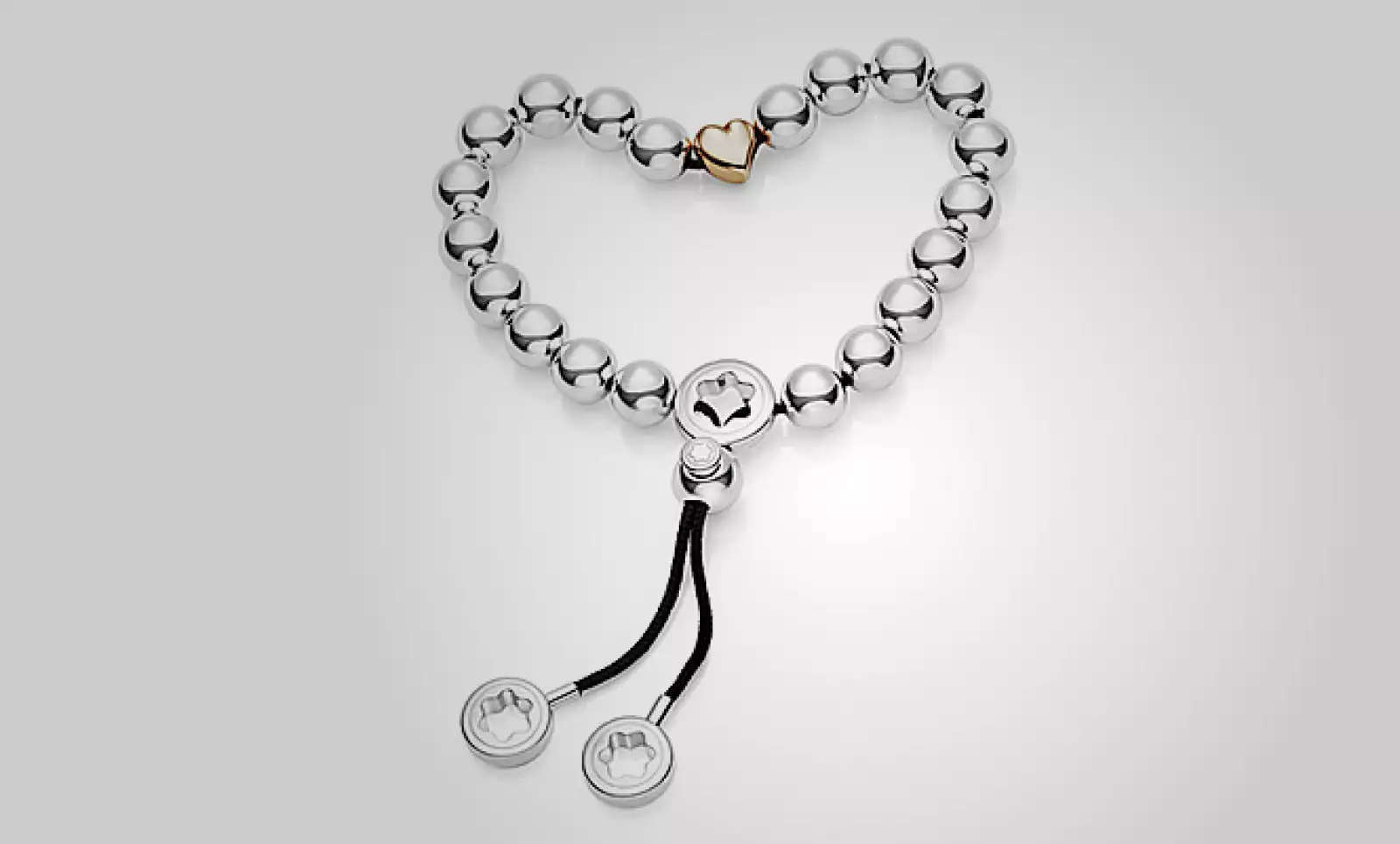 Un brazalete de Montblanc, que tiene perlas de plata entrelazadas, en un hilo de color negro que se cierran en un dije de corazón en color rosa.