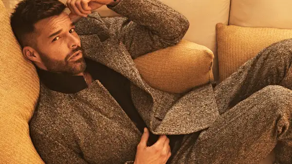 Ricky Martin posa en su casa de Los Ángeles. El cantante puertorriqueño se le ve recostado en un sillón vistiendo un traje gris. 