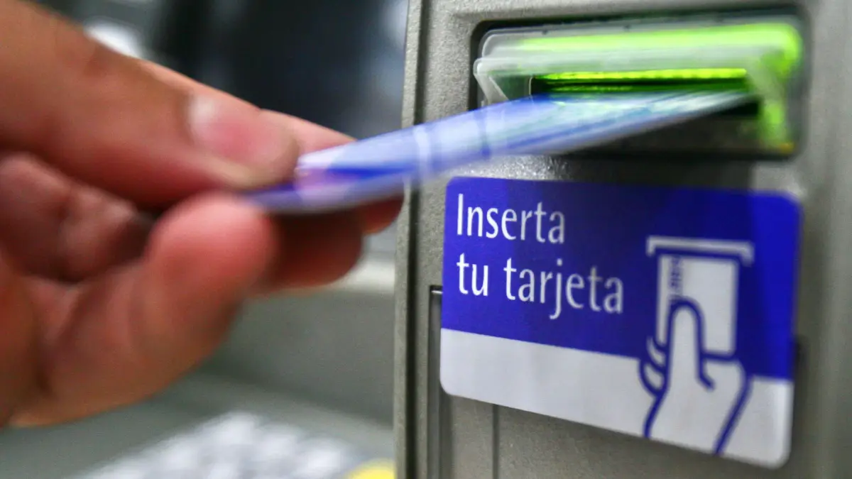 Una personas ingresa una tarjeta bancaria a un cajero automático.