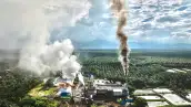 Paisaje con una fábrica que está emitiendo vapor y humo.
